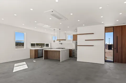a large white kitchen with lots of counter top space and stainless steel appliances
