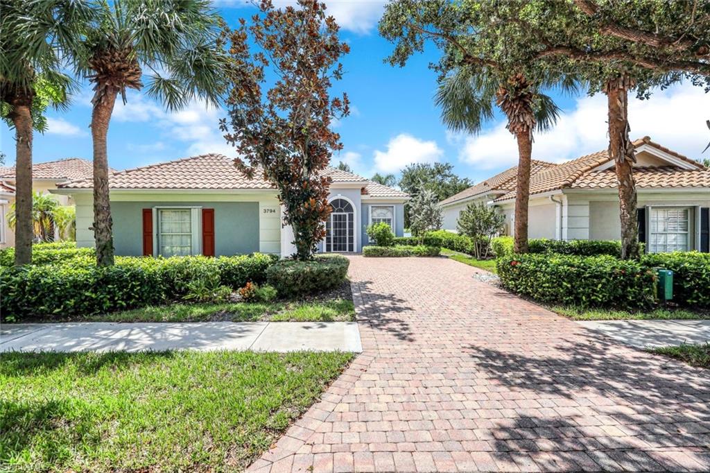 3794 Whidbey Way Naples, FL 34119 - Photo 5 of 46 a front view of a house with a garden and palm trees