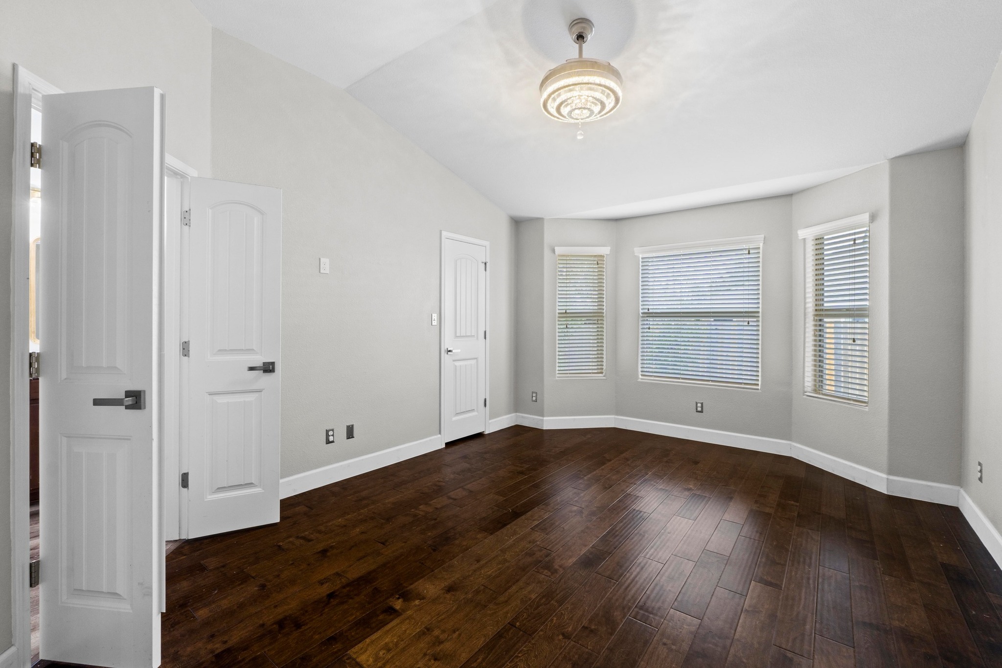 19004 Mangan Way Pflugerville, TX 78660 - Photo 18 of 38 The primary bedroom features rich, dark wood flooring and a beautiful bay window that creates a bright sitting area. The vaulted ceiling and designer lighting add a touch of luxury to your private sanctuary.