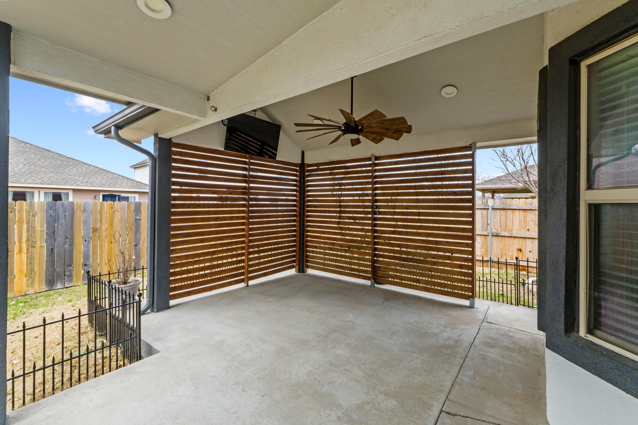 19004 Mangan Way Pflugerville, TX 78660 - Photo 28 of 38 Step outside to your private covered patio, an ideal spot for year-round entertaining. Featuring a custom wood privacy screen, an oversized ceiling fan, and a mounted TV, this is the perfect outdoor retreat.