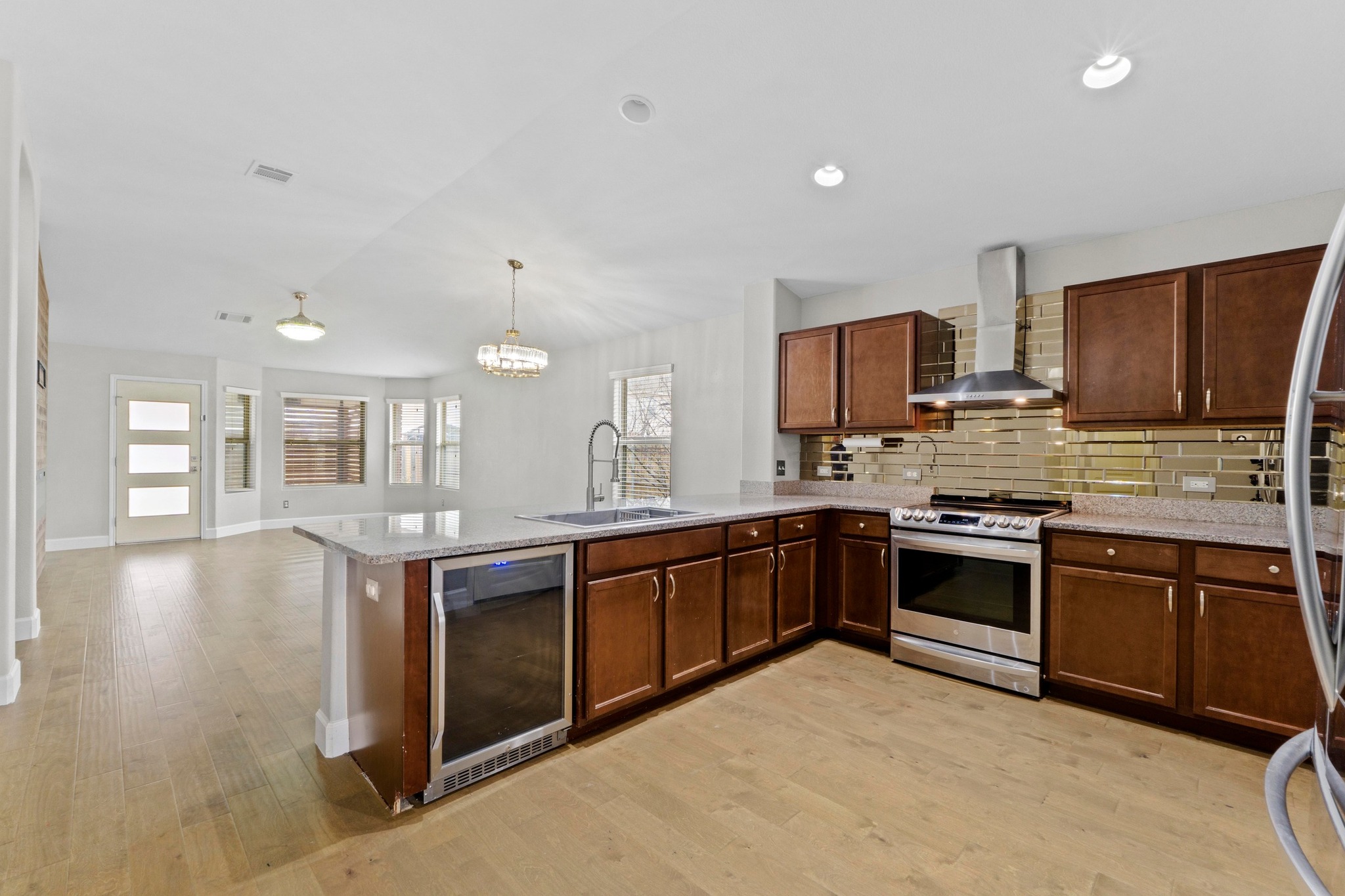 19004 Mangan Way Pflugerville, TX 78660 - Photo 5 of 38 This impressive open-concept kitchen is the heart of the home. Equipped with stainless steel appliances, premium granite countertops, and a built-in wine fridge, it’s perfect for entertaining.