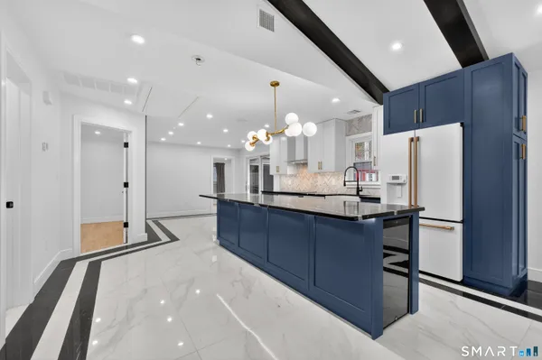 a kitchen with stainless steel appliances kitchen island granite countertop a refrigerator and a sink