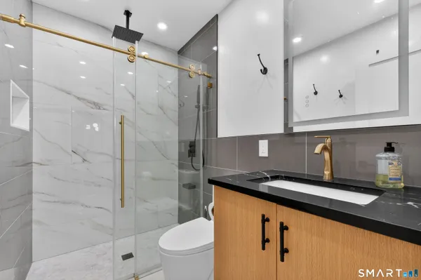 a bathroom with a granite countertop sink a toilet and shower