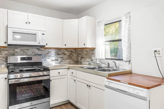 a kitchen with cabinets appliances a sink and a counter top space