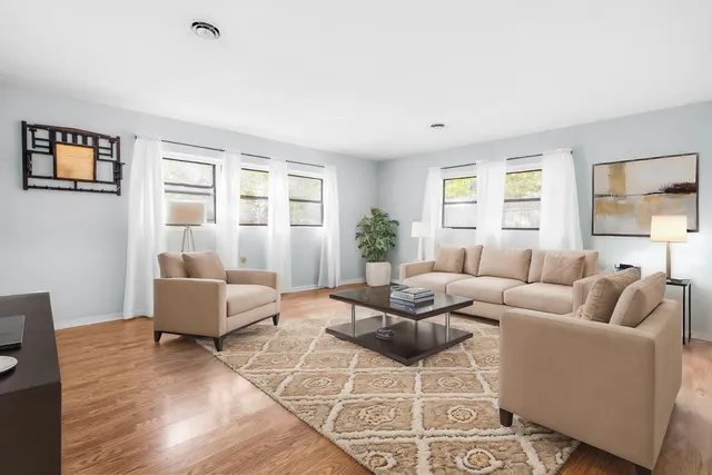 a living room with furniture a large window and a wooden floor
