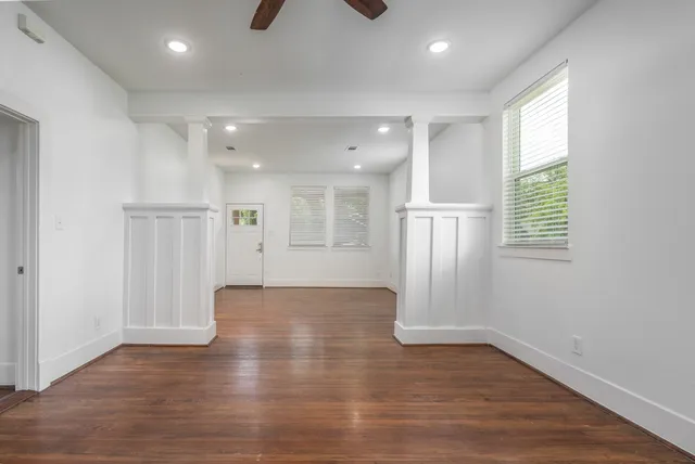 a view of an empty room with wooden floor and a window