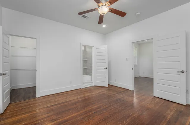 an empty room with wooden floor closet and windows
