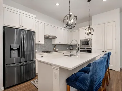 a kitchen with stainless steel appliances a stove a refrigerator a sink and a center island