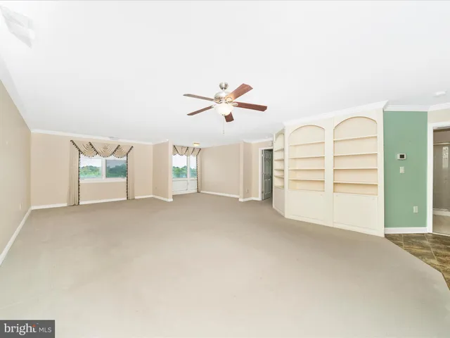 an empty room with a ceiling fan and window