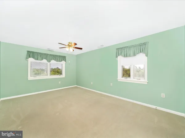a view of a big room with windows and ceiling fan