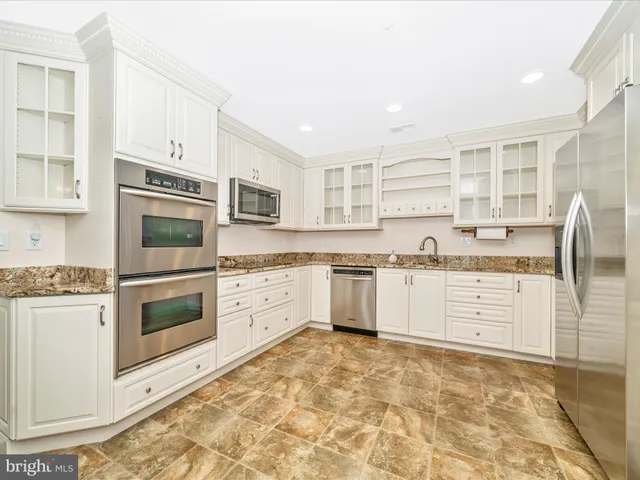 a kitchen with granite countertop white cabinets and stainless steel appliances