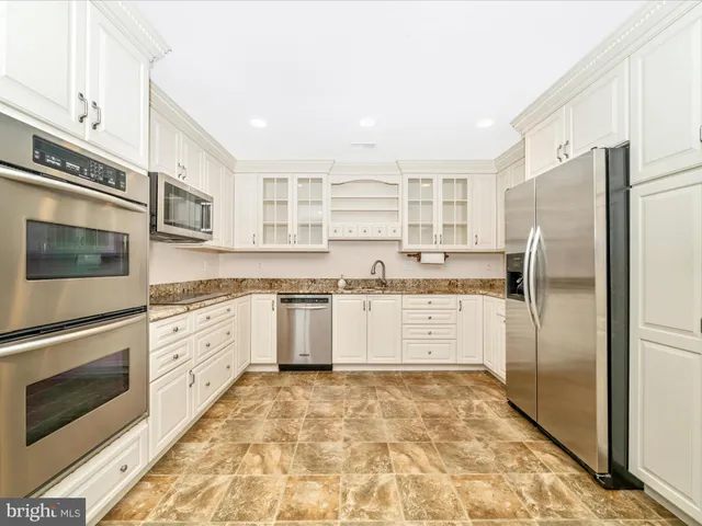 a large kitchen with cabinets stainless steel appliances and a window