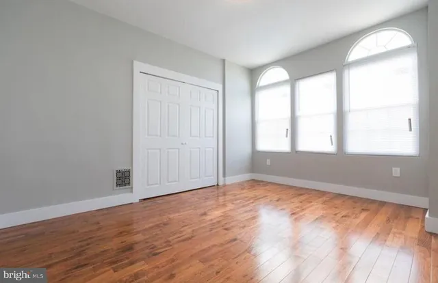 an empty room with wooden floor and windows
