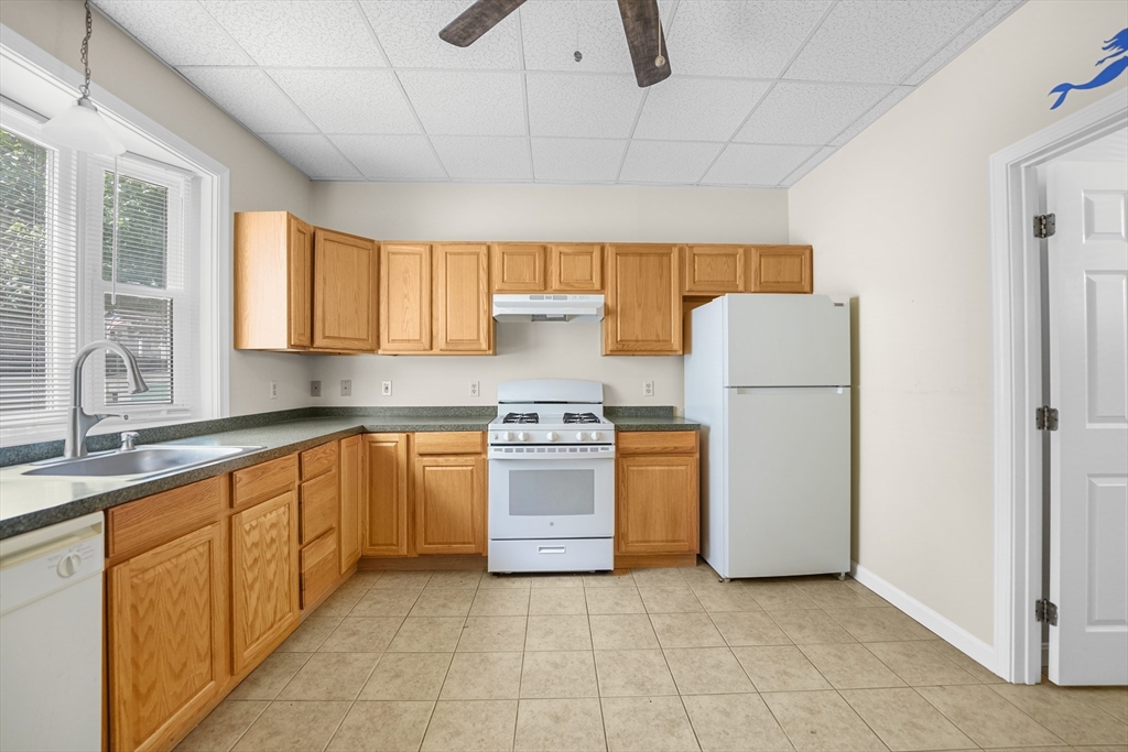 216 Grove Street Fall River, MA 02720 - Photo 7 of 26 a kitchen with a refrigerator a stove a sink dishwasher and wooden cabinets