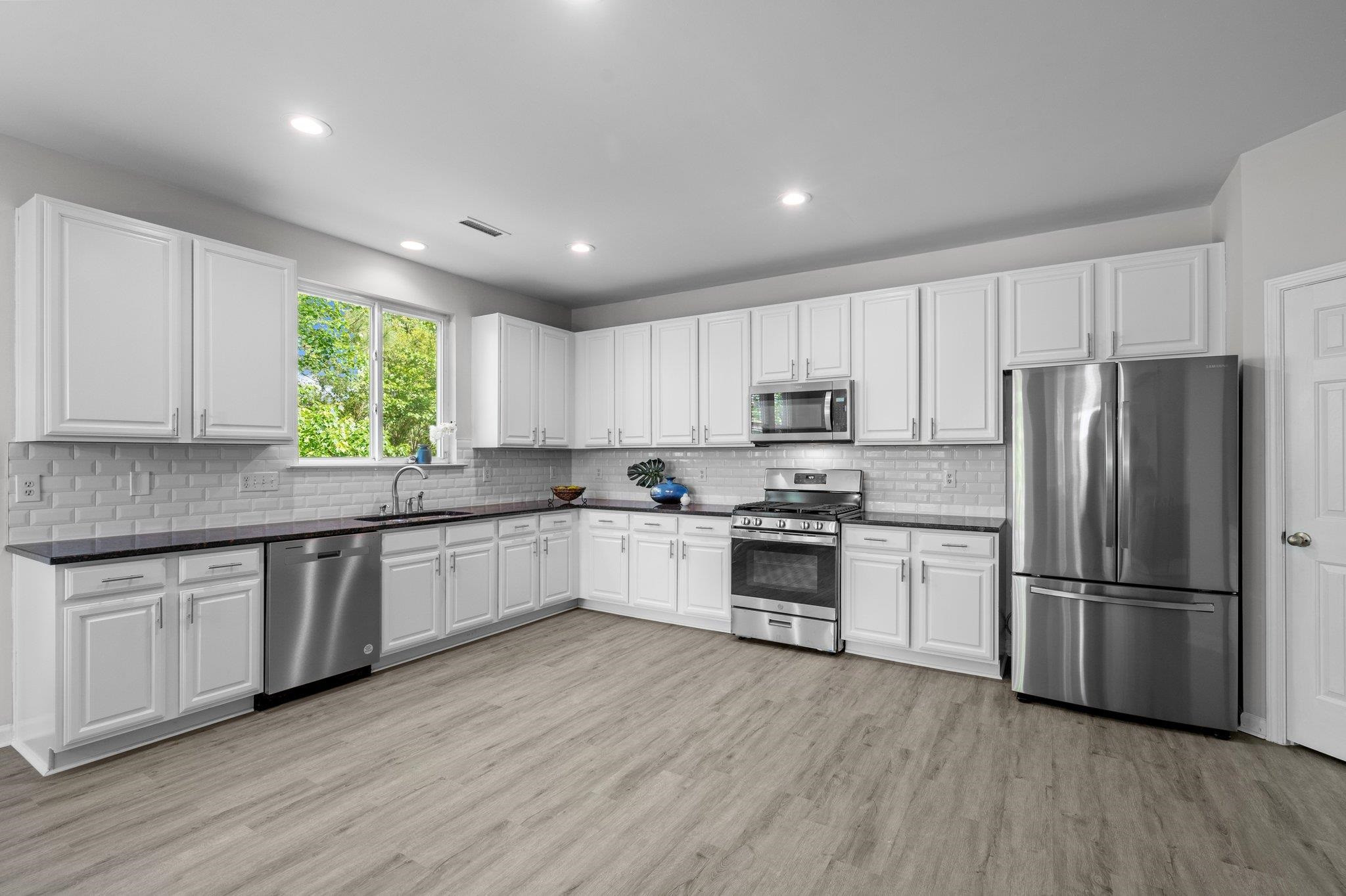 532 Emerald Downs Road Cary, NC 27519 - Photo 21 of 51 a kitchen with granite countertop a refrigerator a sink dishwasher a stove and white cabinets with wooden floor