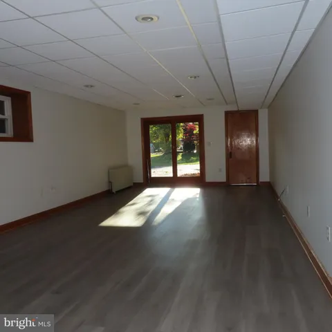a view of an empty room with wooden floor and a fireplace