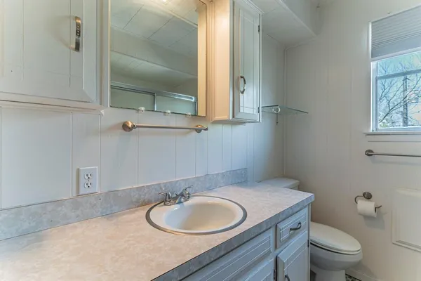 a bathroom with a granite countertop toilet sink mirror and vanity