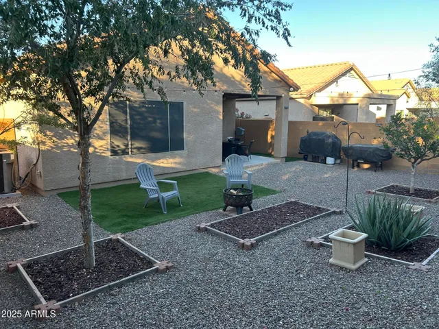 a view of a backyard with table and chairs potted plants and large tree