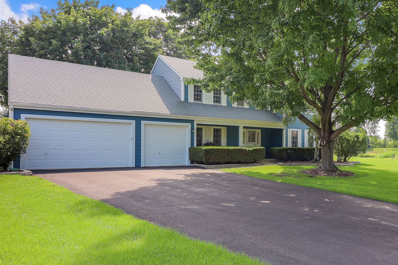 a front view of a house with a garden and trees