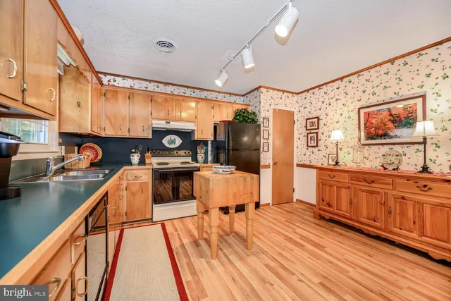 a kitchen with stainless steel appliances granite countertop a stove a sink dishwasher and a microwave with wooden floor