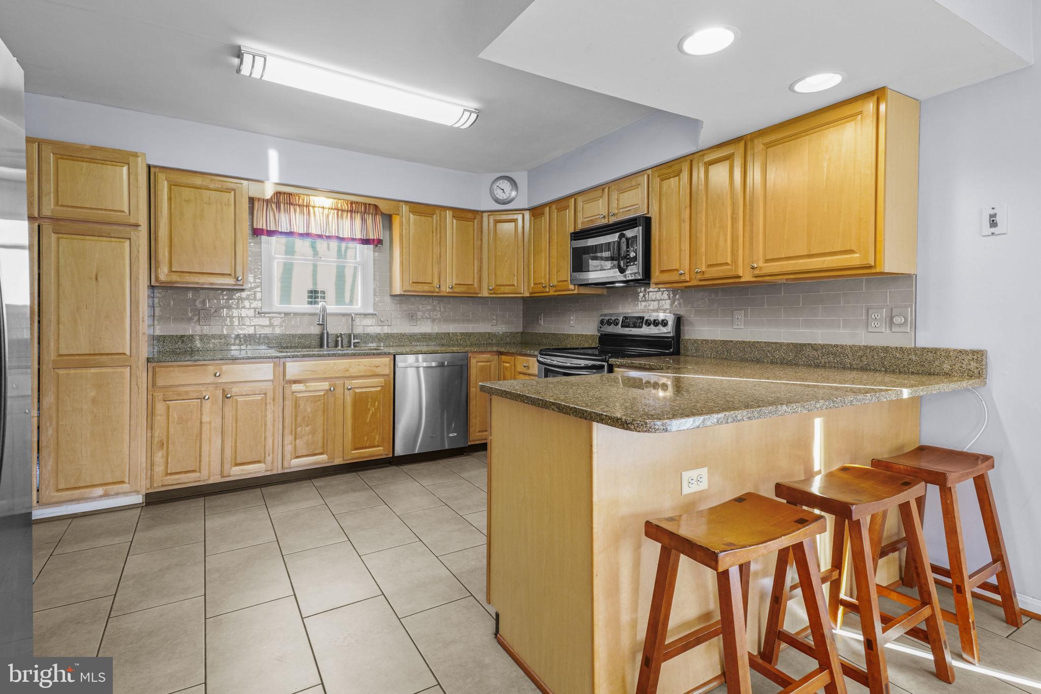 939 Main Street Deale, MD 20751 - Photo 18 of 37 a kitchen with stainless steel appliances granite countertop a sink a stove a refrigerator cabinets and a window