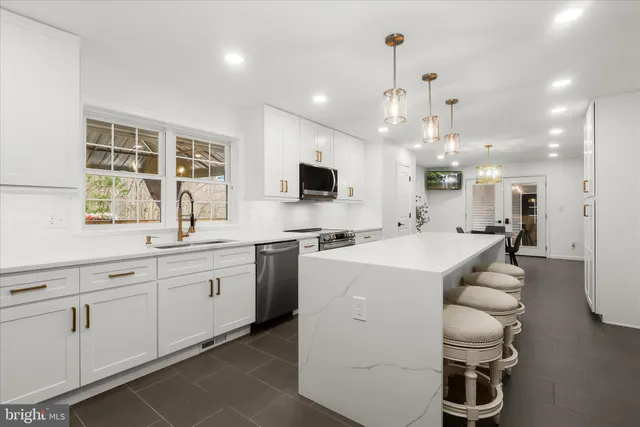 a large kitchen with stainless steel appliances a stove a sink dishwasher and a refrigerator with wooden floor