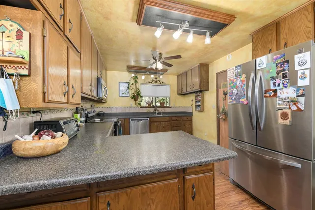 a kitchen with stainless steel appliances granite countertop a sink a refrigerator and a wooden cabinets