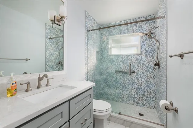 a bathroom with a sink vanity granite toilet and shower