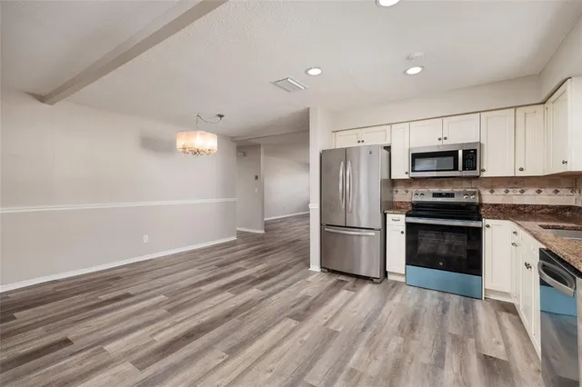 a kitchen with granite countertop a refrigerator and a stove top oven