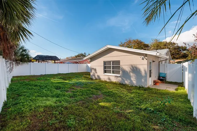 a view of a backyard with plants and a large tree