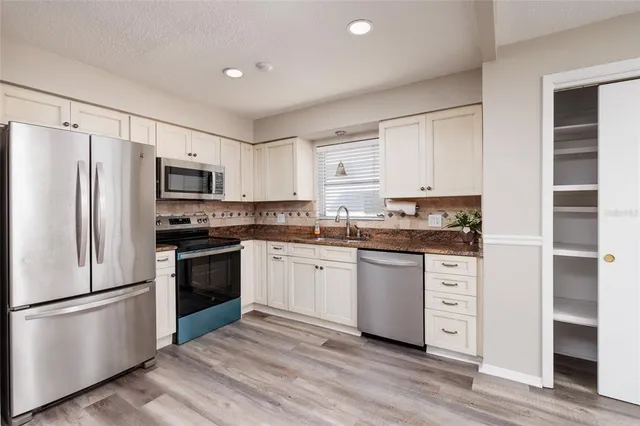 a kitchen with a refrigerator stove and white cabinets