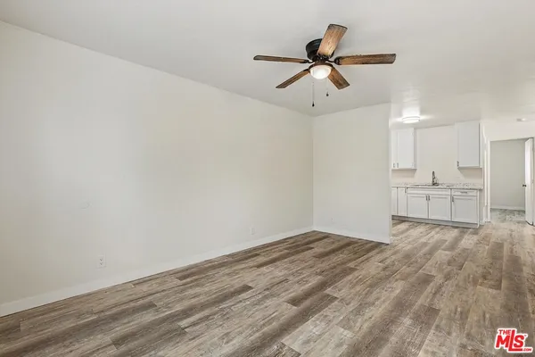 a view of empty room with wooden floor and ceiling fan