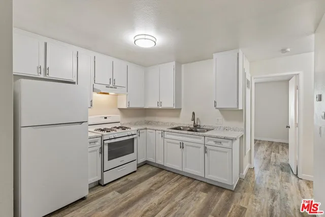 a kitchen with a sink cabinets stainless steel appliances and wooden floor