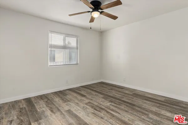 an empty room with chandelier fan and windows