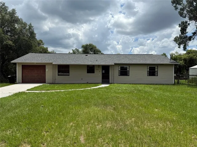a view of a house with a yard and large tree
