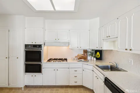 a kitchen with granite countertop white cabinets and stainless steel appliances