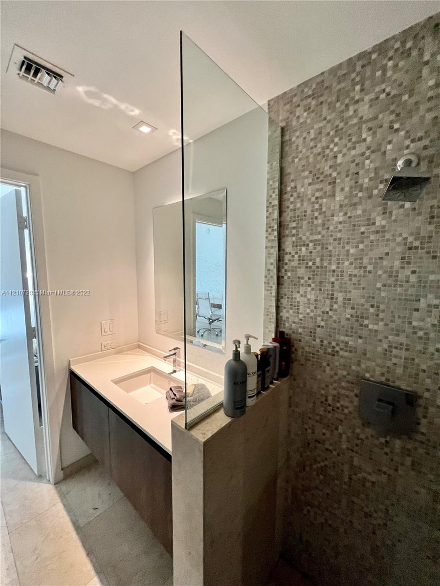 68 Southeast 6th Street, Unit 2801 Miami, FL 33131 - Photo 21 of 40 a bathroom with a granite countertop sink a mirror and a shower