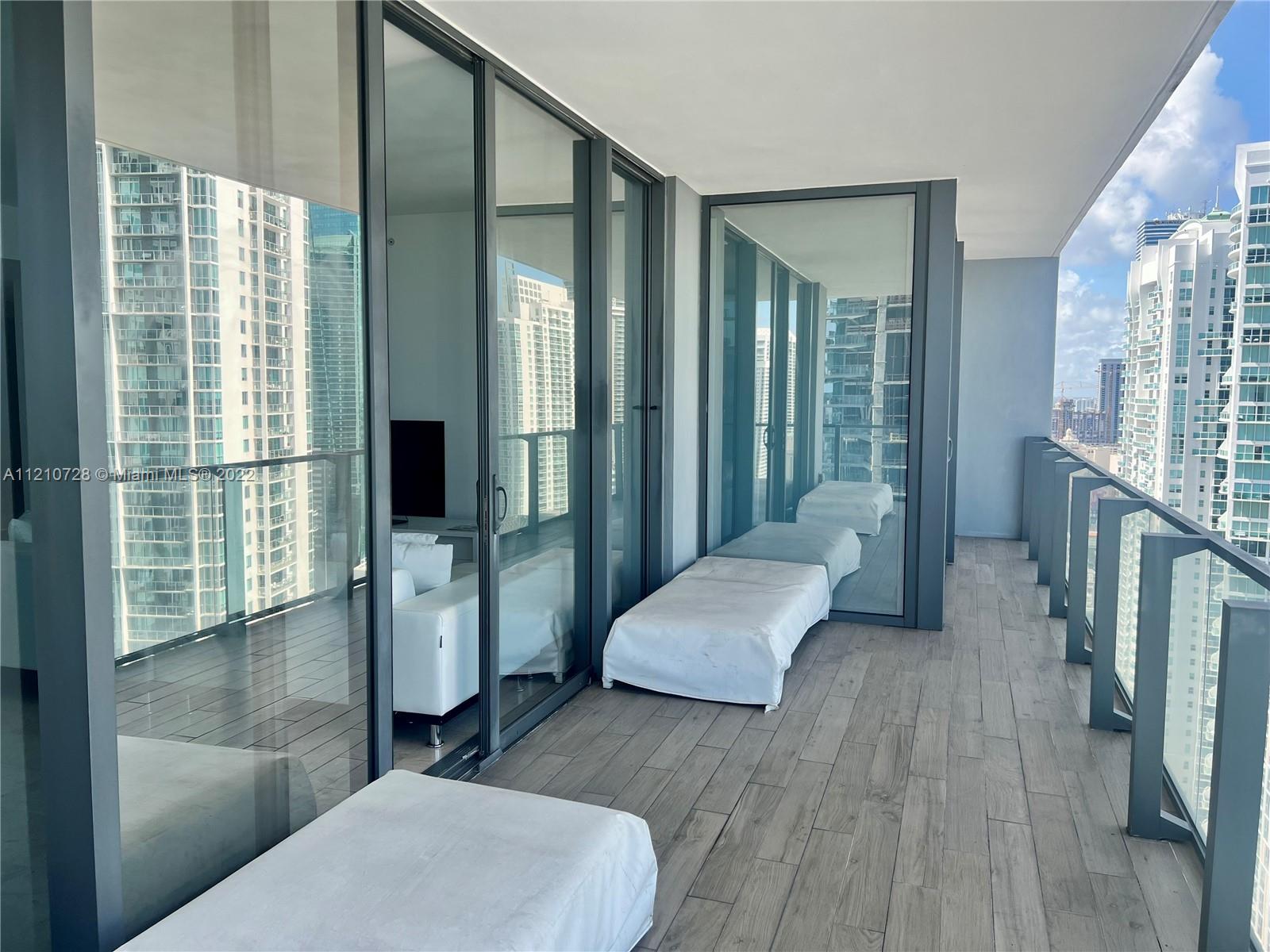 68 Southeast 6th Street, Unit 2801 Miami, FL 33131 - Photo 34 of 40 a spacious bedroom with a large bed and a wooden floor