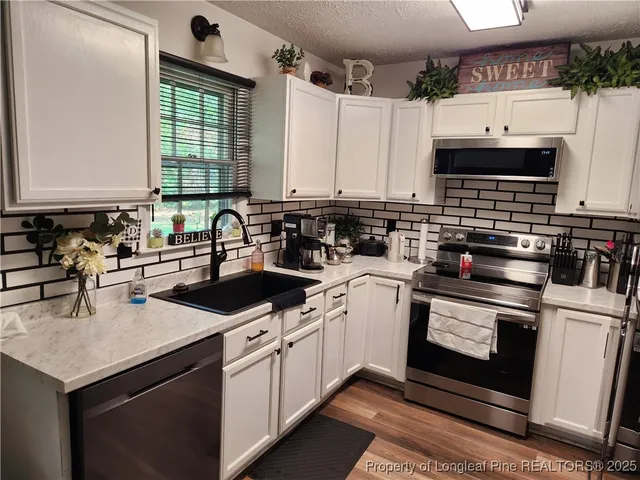 a kitchen with stainless steel appliances a stove a sink a microwave and cabinets