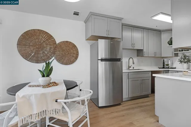 a kitchen with stainless steel appliances granite countertop a refrigerator a sink a stove a dining table and chairs