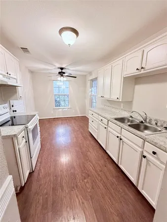 a kitchen with granite countertop a sink cabinets wooden floor and stainless steel appliances