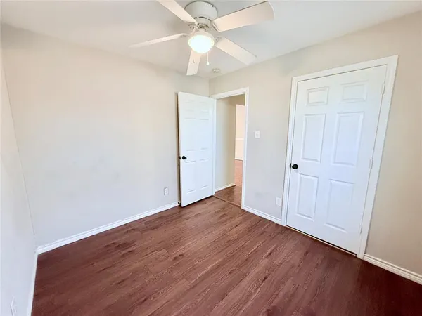 an empty room with wooden floor fan and windows