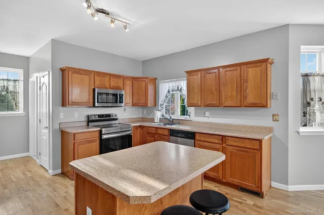 a kitchen with stainless steel appliances granite countertop a sink dishwasher stove refrigerator and microwave with wooden floor