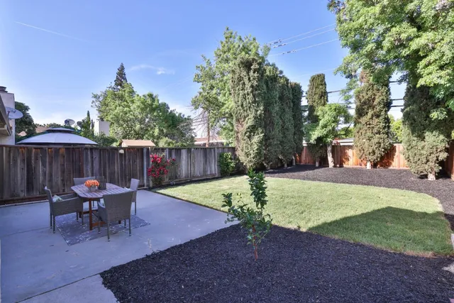 a view of a backyard with table and chairs under an umbrella