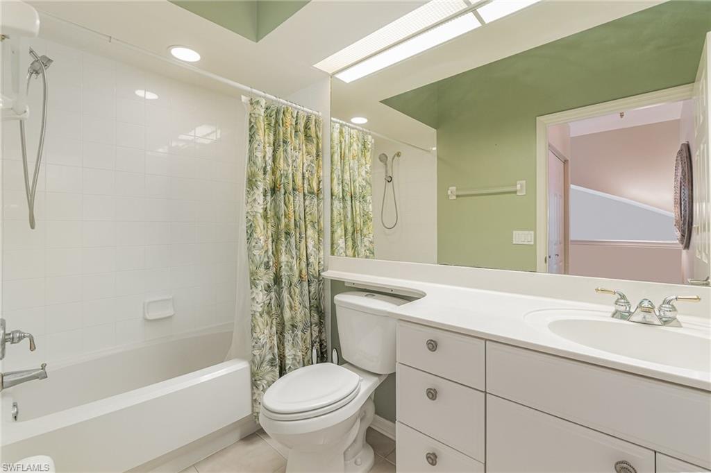 10921 Oak Island Road, Unit 203 Estero, FL 34135 - Photo 16 of 25 a bathroom with a granite countertop sink a toilet a mirror a bathtub and shower