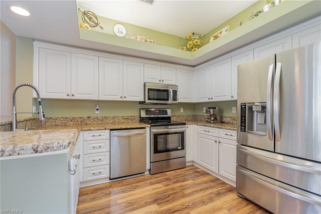 10921 Oak Island Road, Unit 203 Estero, FL 34135 - Photo 8 of 25 a kitchen with granite countertop stainless steel appliances and wooden cabinets