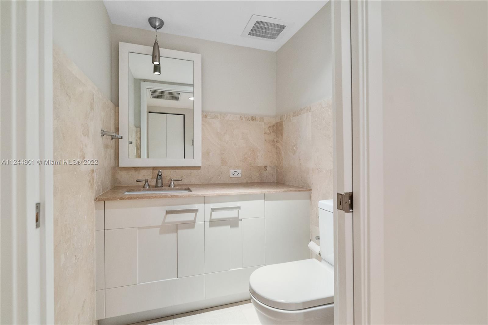 3540 Main Highway, Unit 309 Miami, FL 33133 - Photo 12 of 34 a bathroom with a granite countertop toilet sink and mirror