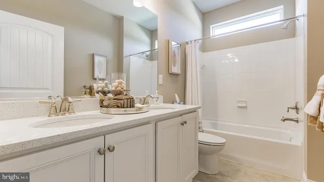 a bathroom with a double vanity sink toilet mirror and bathtub