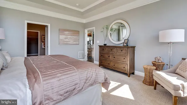 a bedroom with a bed a mirror on dresser and a window
