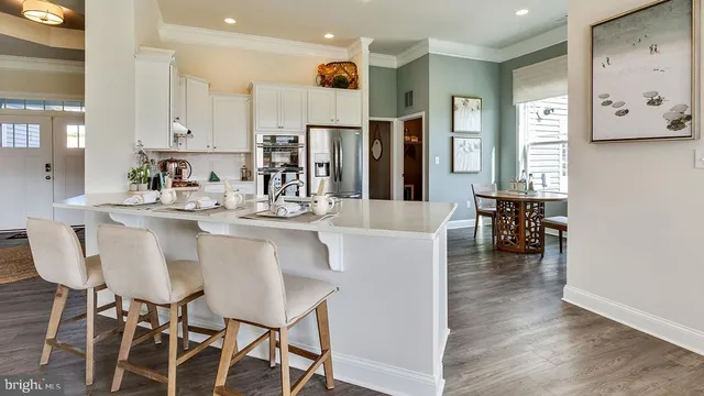 a kitchen with stainless steel appliances kitchen island granite countertop a dining table chairs and a refrigerator